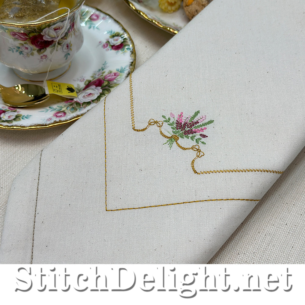 Embroidered napkin with floral design next to a teacup and saucer.