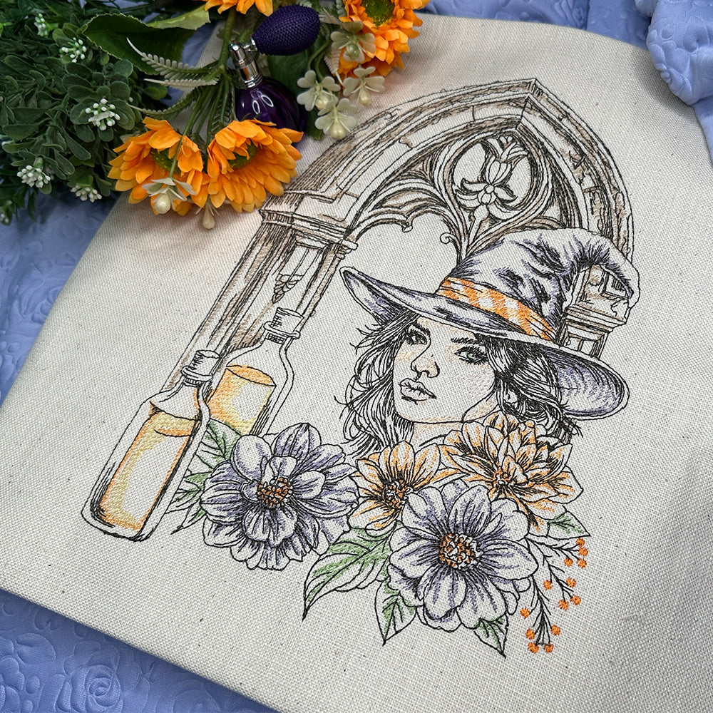 Embroidery of a witch with flowers and a bottle on fabric with flowers around.