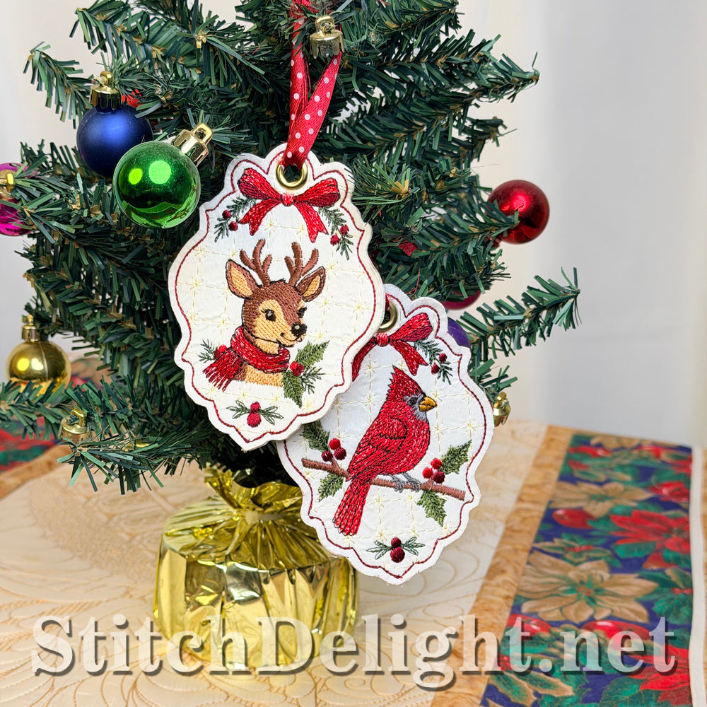 Embroidered deer tag and cardinal tag hanging together from a red polka-dot ribbon on a small Christmas tree with baubles