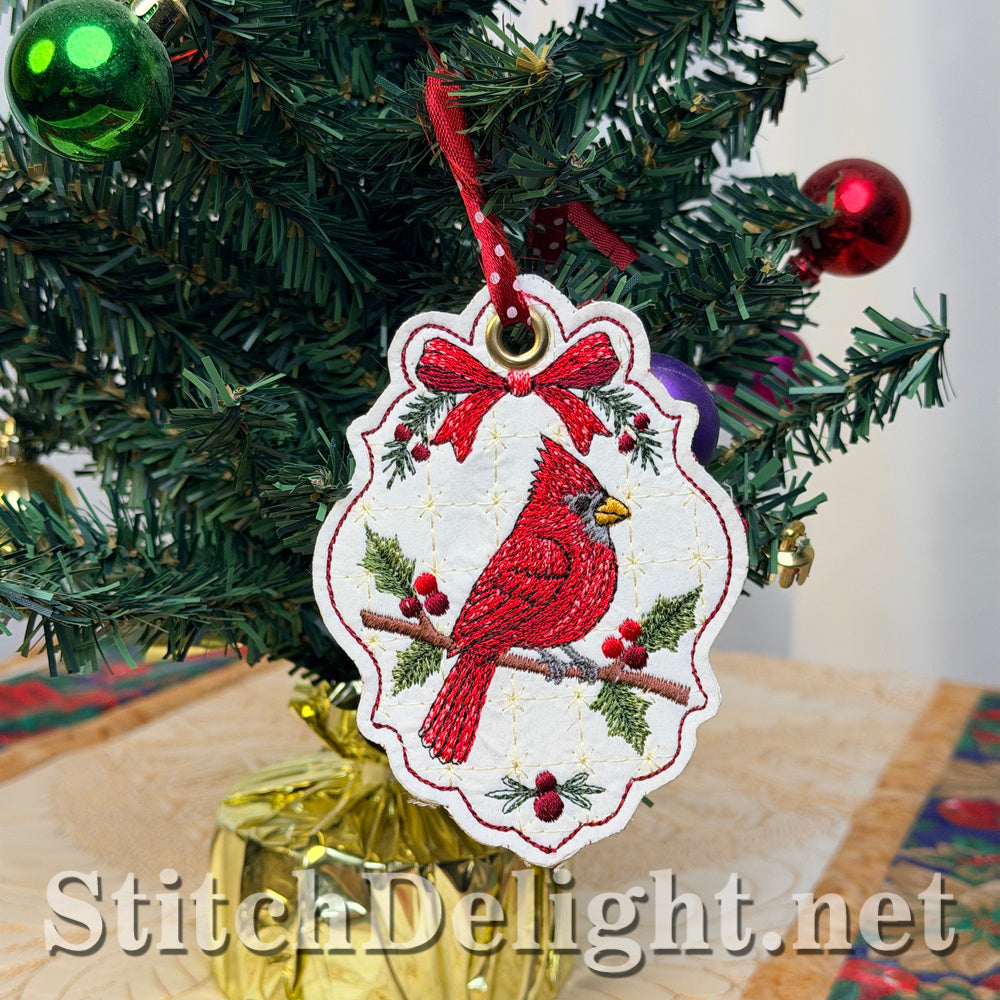 Cardinal Christmas tag hanging from a red polka-dot ribbon on a decorated miniature Christmas tree, with the cardinal perched on a holly branch beneath a red bow