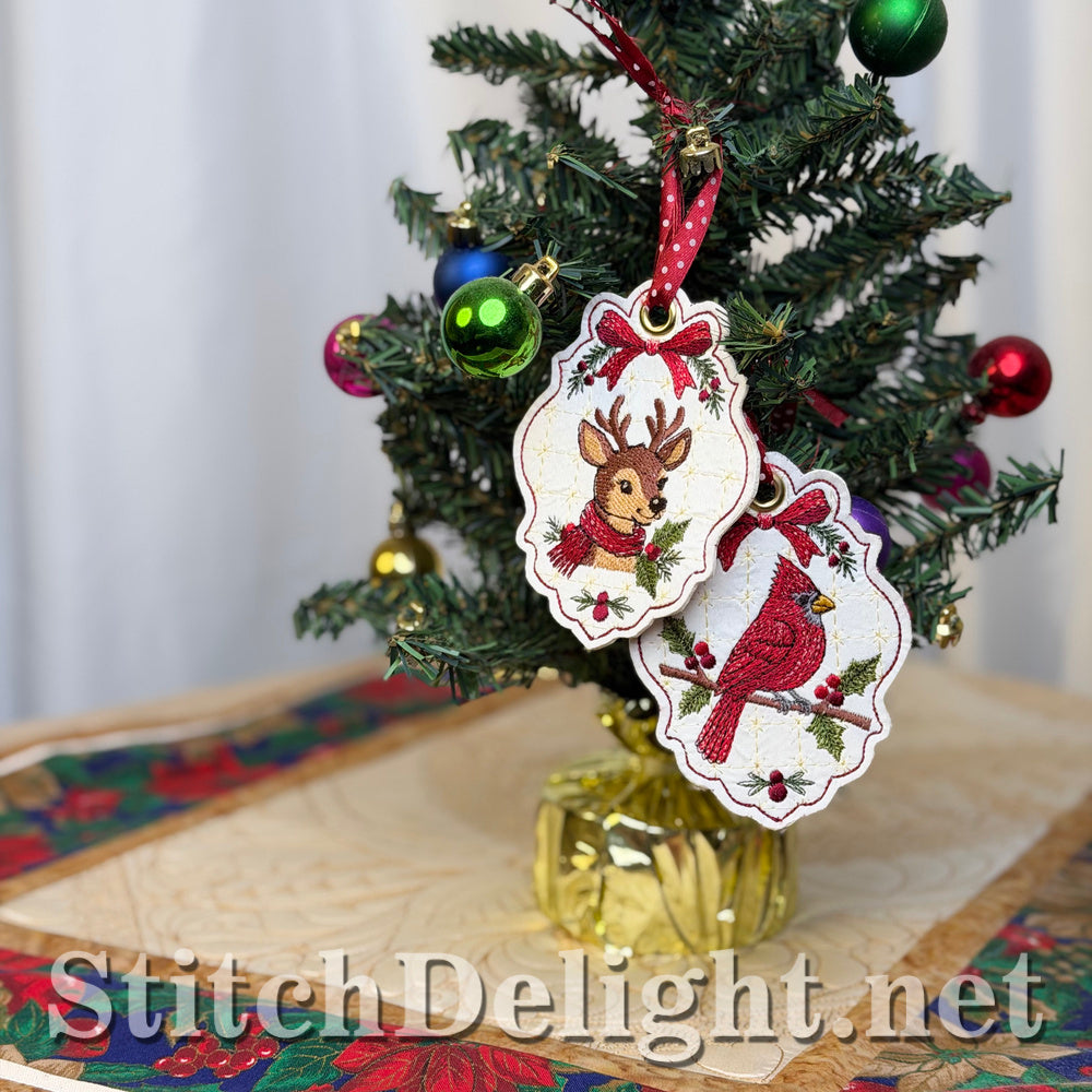 Matching deer and cardinal Christmas tags with red bows and holly hanging side by side on a miniature Christmas tree