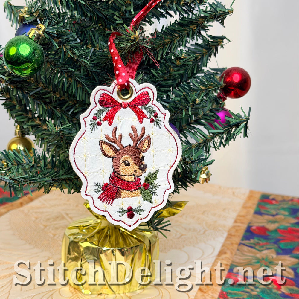 Deer Christmas tag with a red bow and polka-dot ribbon hanging from a small decorated tree on a Christmas table runner